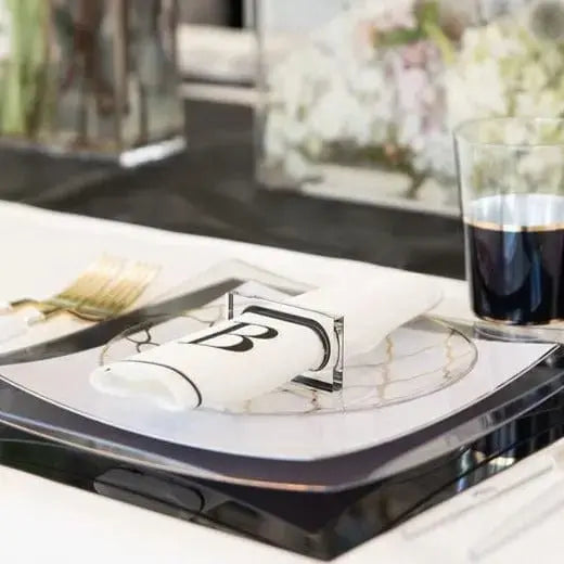 Rectangle napkin rings with black border displayed on white napkin with eyeglasses and flowers in background.