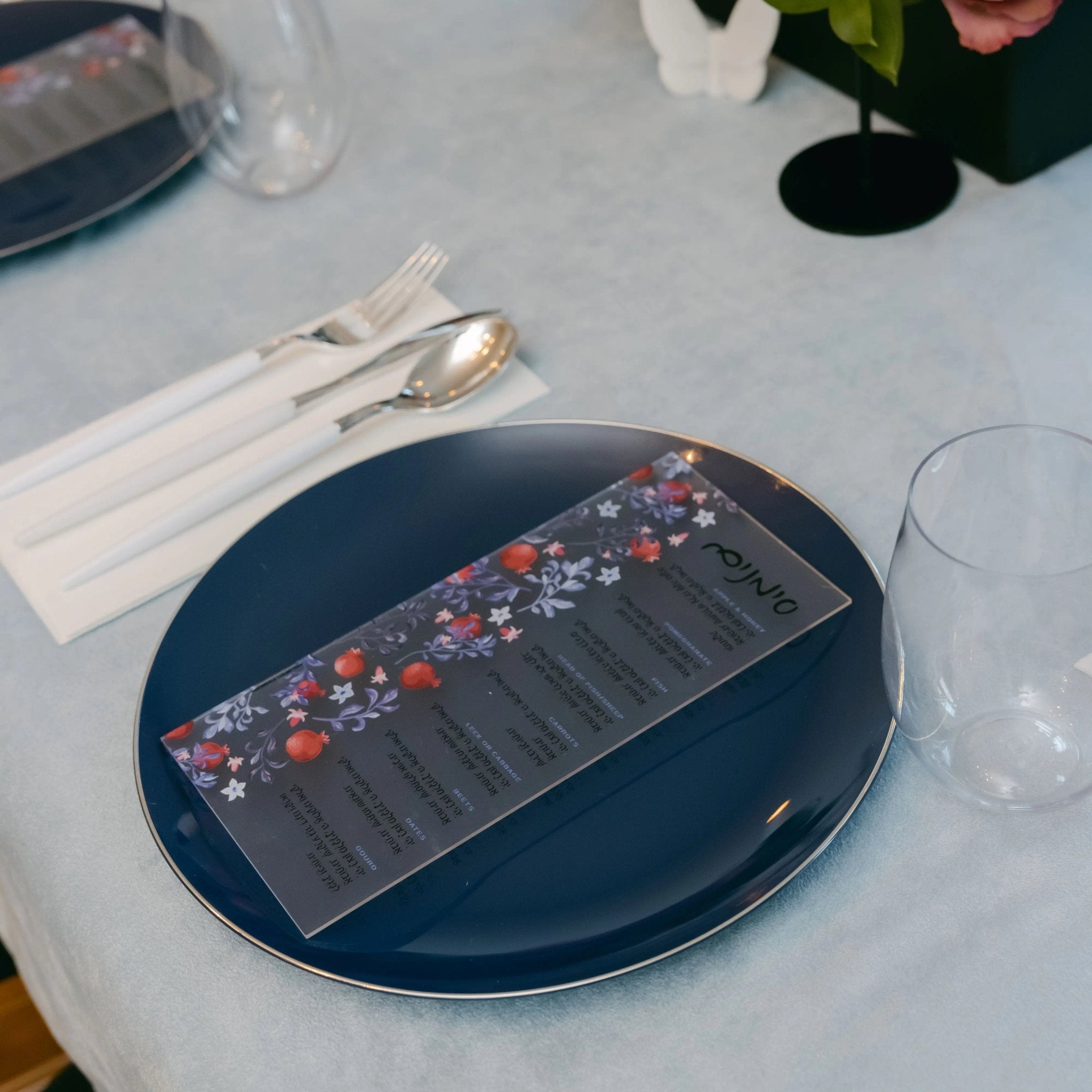 Navy lucite Artistic Simanim Card by Waterdale Collection displaying traditional Passover symbols in elegant design on white table setting.