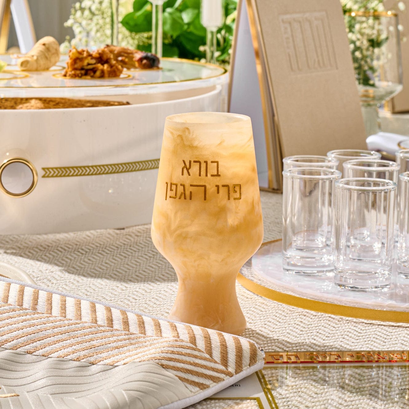 Resin Havdalah or Kiddush cup with marbled finish and gold Hebrew lettering, displayed beside a gold candle holder and glass decanter.