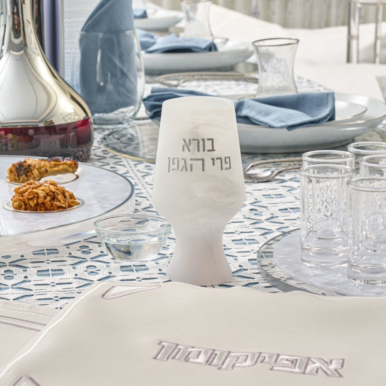 White marbled resin Havdalah or Kiddush cup with Hebrew lettering, displayed on an elegant Shabbos table setting.