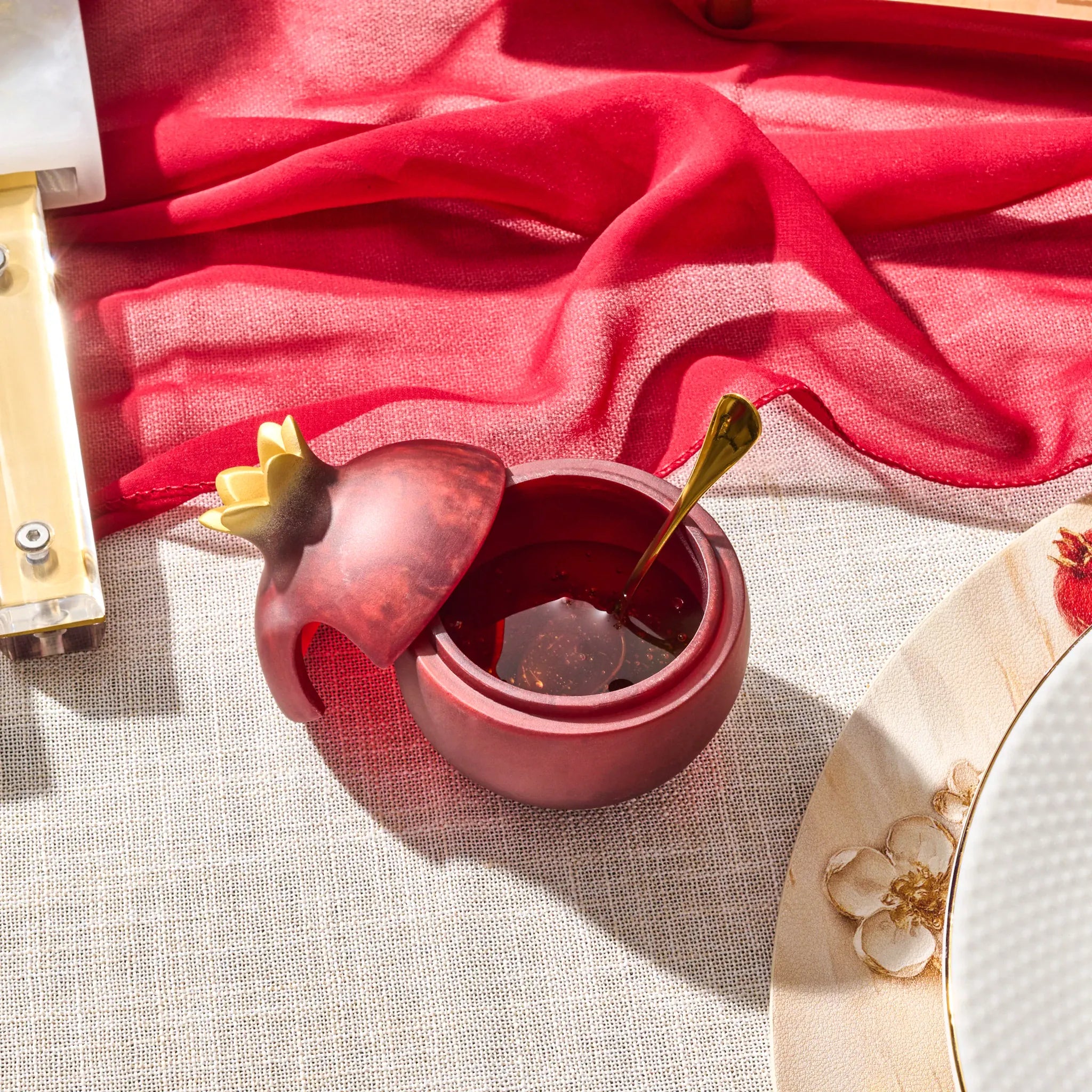 Pomegranate-shaped deep red resin honey dish with a matching spoon for Rosh Hashana