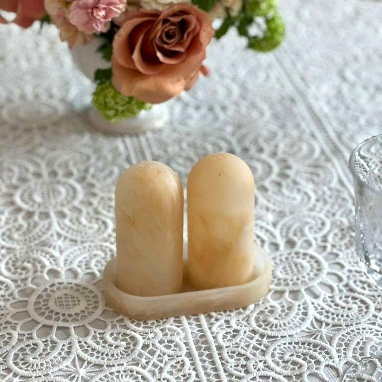 Resin salt and pepper shaker set with a matching oval tray, featuring a cream marbled stone finish on a white lace tablecloth.