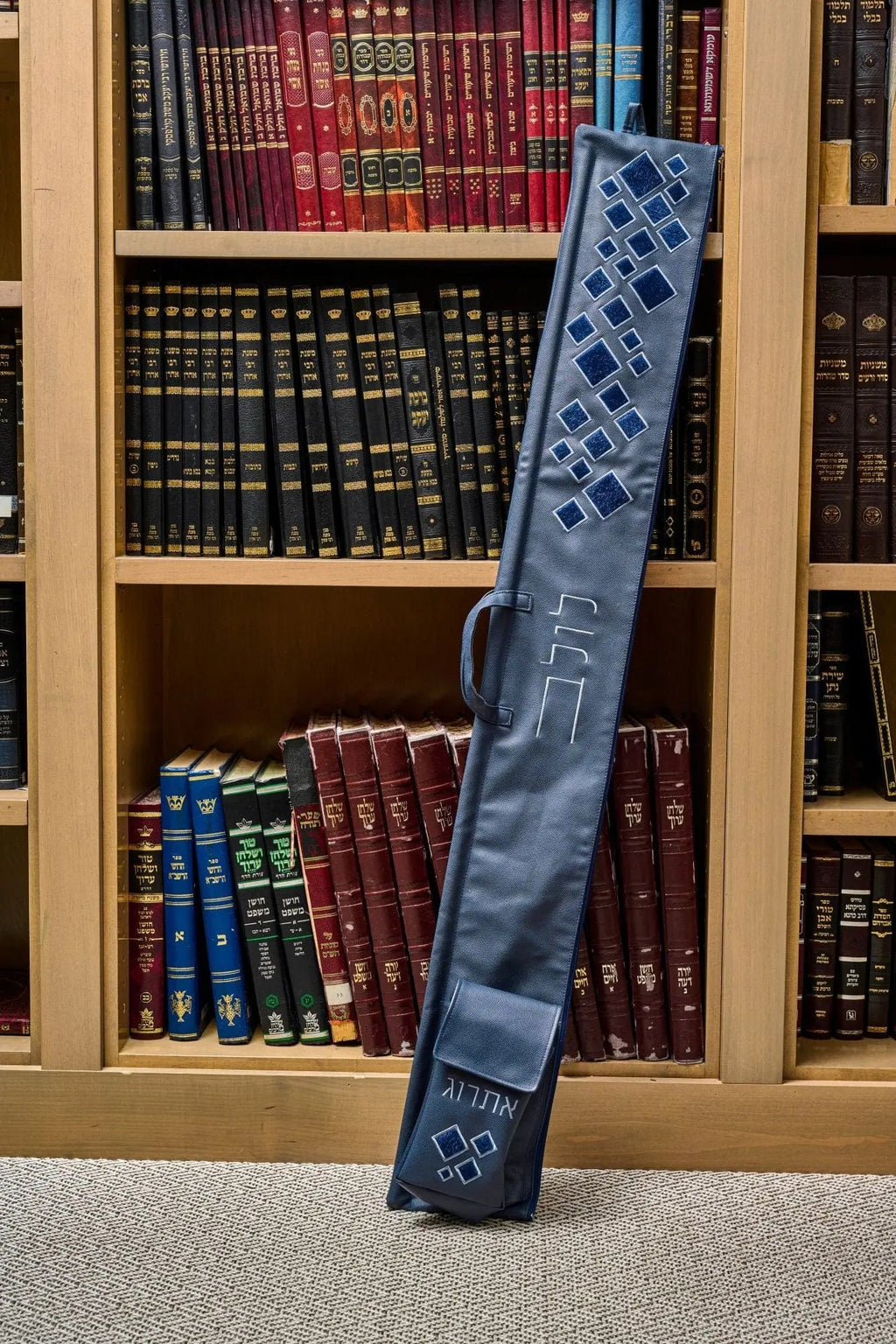 Scattered Fur Lulav and Esrog Case in gray leather leaning against wooden bookshelf display, Sukkot holiday accessory.