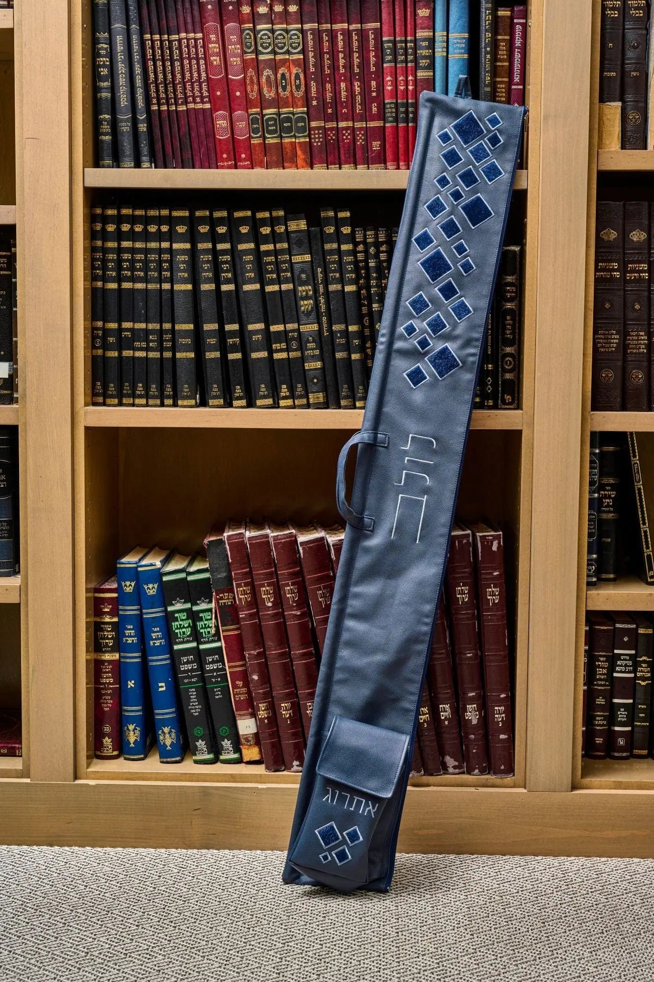 Scattered Fur Lulav and Esrog Case in gray leather leaning against wooden bookshelf display, Sukkot holiday accessory.