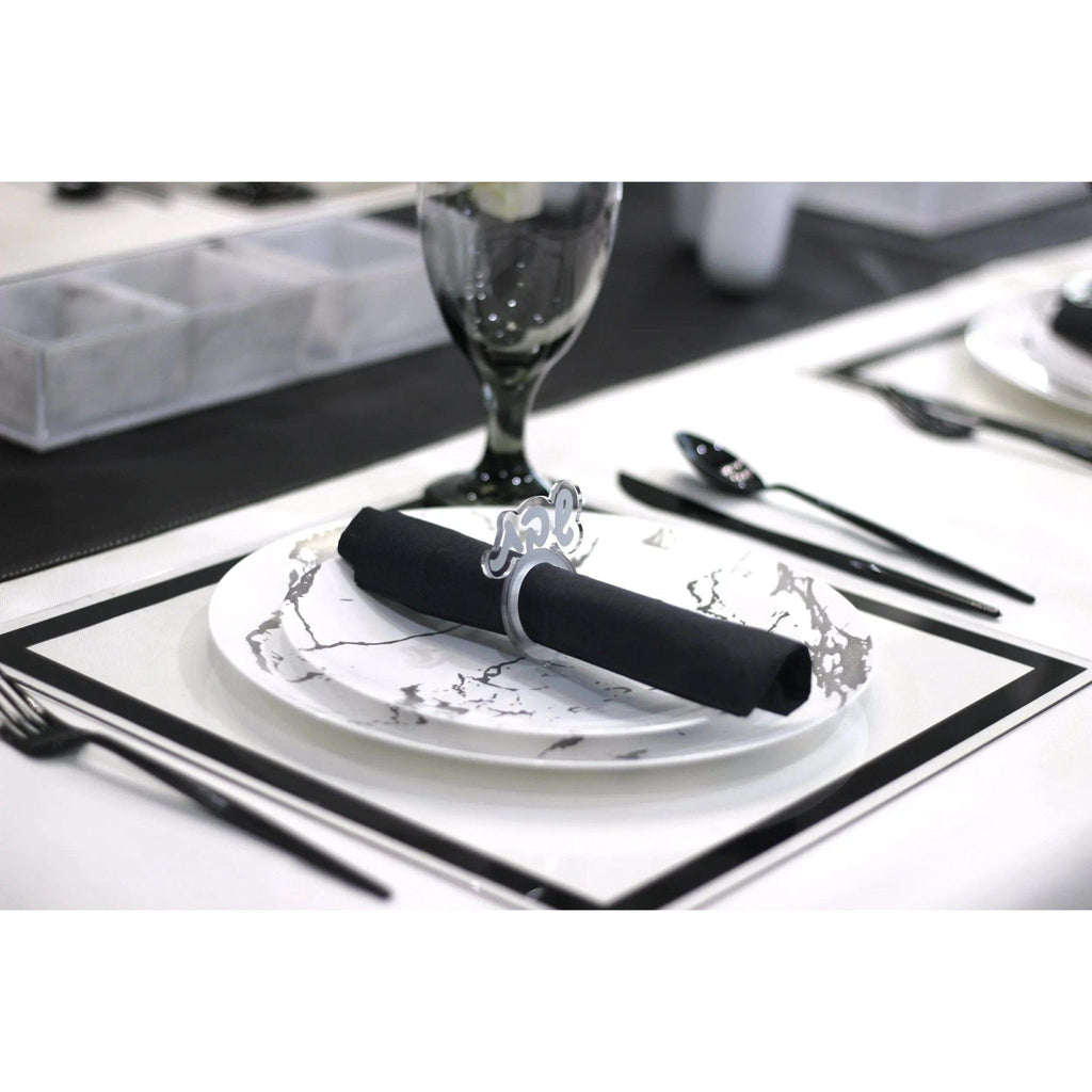Elegant silver Shabbos napkin ring holding a black napkin on a formal place setting with white plate and silverware.