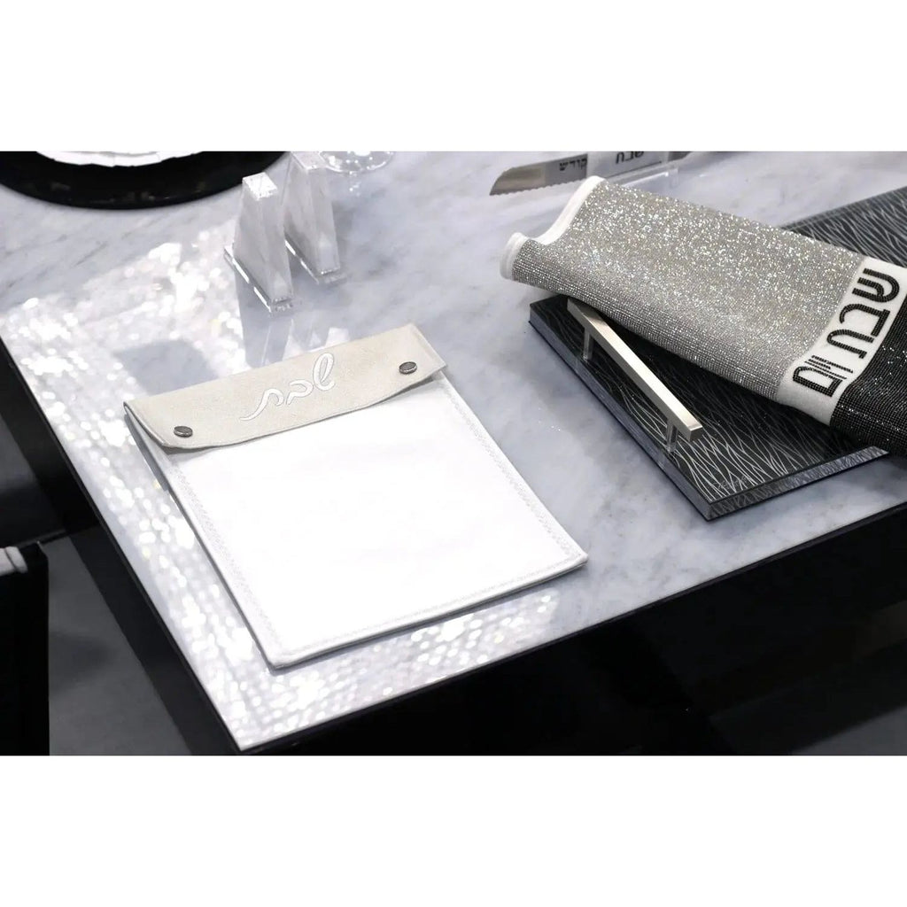 Silver leather Shabbos pouch displayed with white cloth, perfect for organizing Shabbat essentials and holiday gifts.