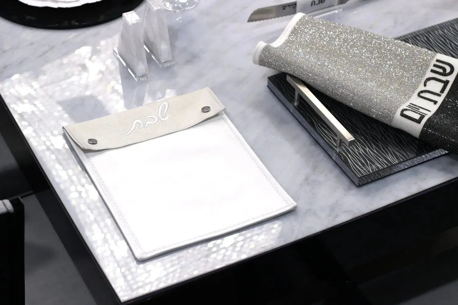 Silver leather Shabbos pouch displayed with white cloth, perfect for organizing Shabbat essentials and holiday gifts.