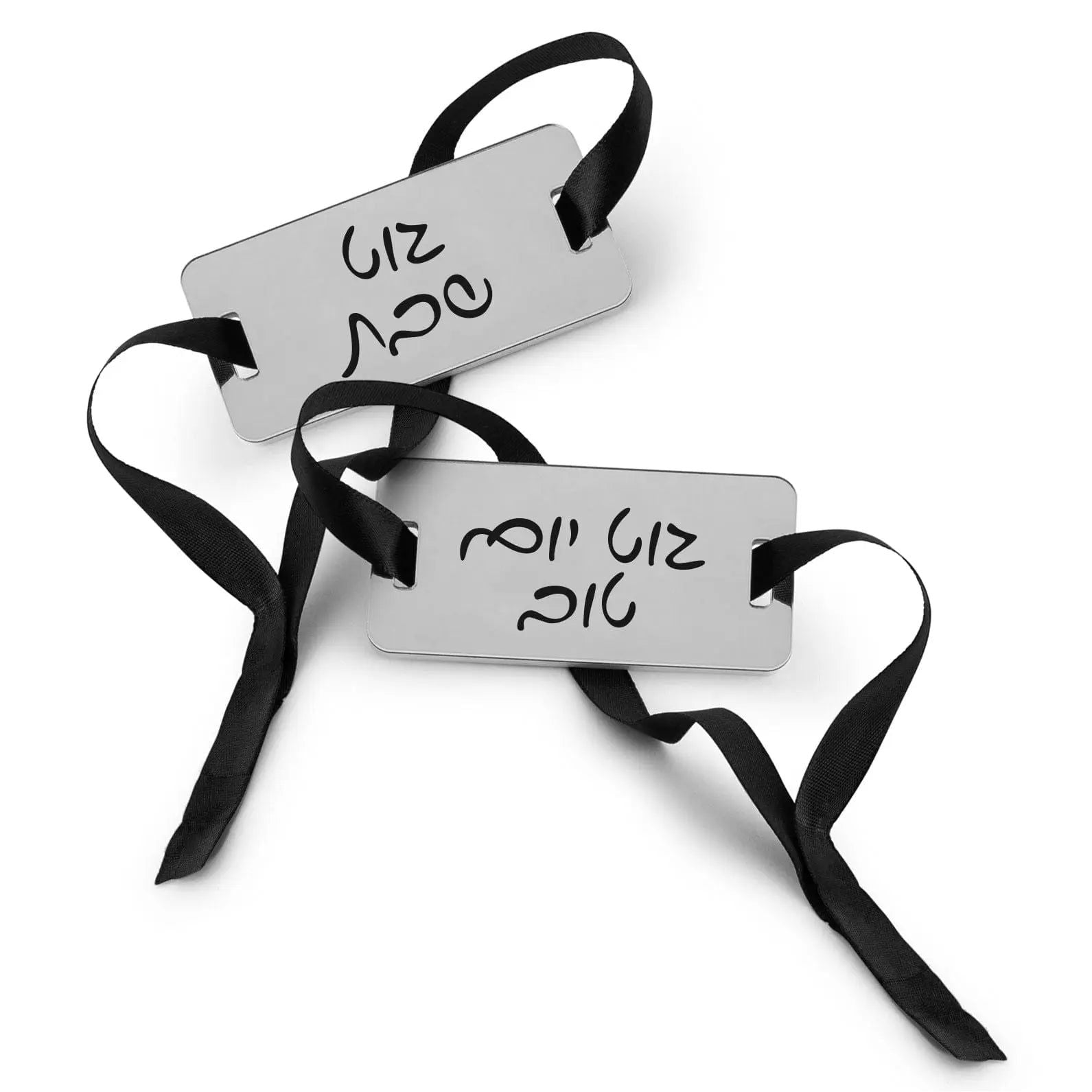 Shabbos Yom Tov napkin wraps in white with black straps and Hebrew text, displayed as a pair of napkin rings for holiday table settings.