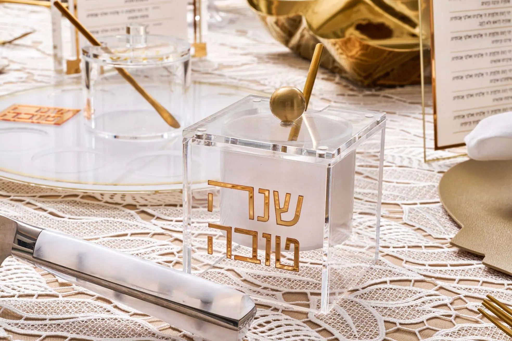 Suspended honey dish in brass with geometric design on architectural blueprints and design materials, Waterdale Collection tabletop judaica.