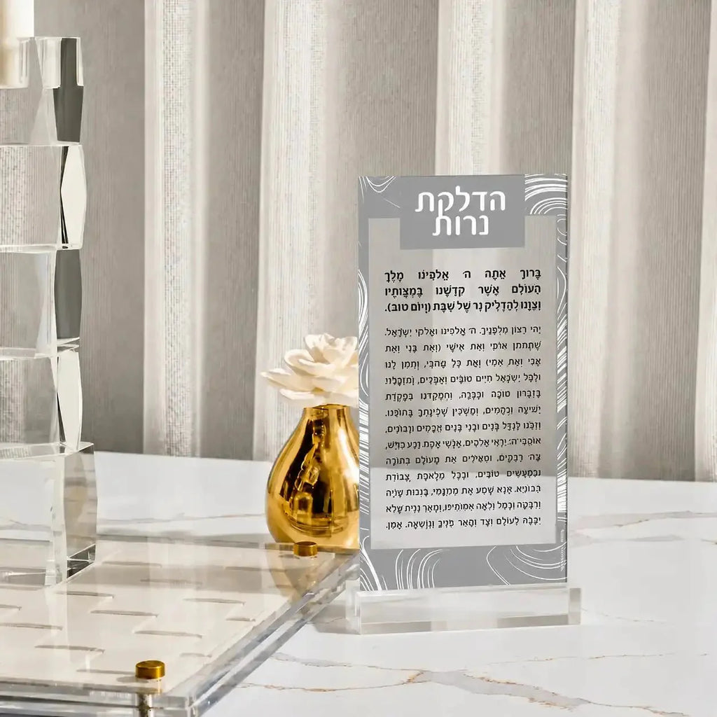Silver and gold lucite Hadlokas Neiros card displayed with cream flower in gold vase on marble surface