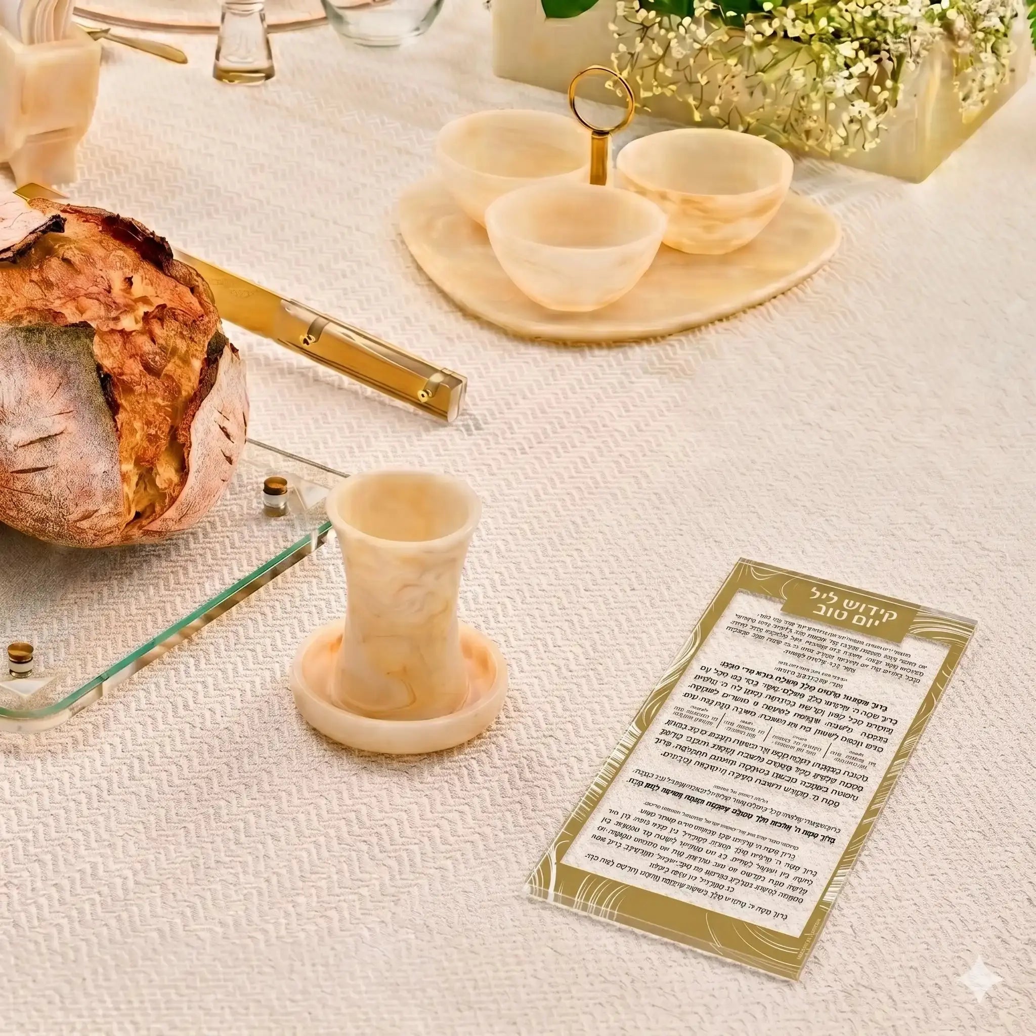 Gold swirl lucite Kiddush Yom Tov card displayed on white table with challah bread and ceremonial cups for holiday meals.
