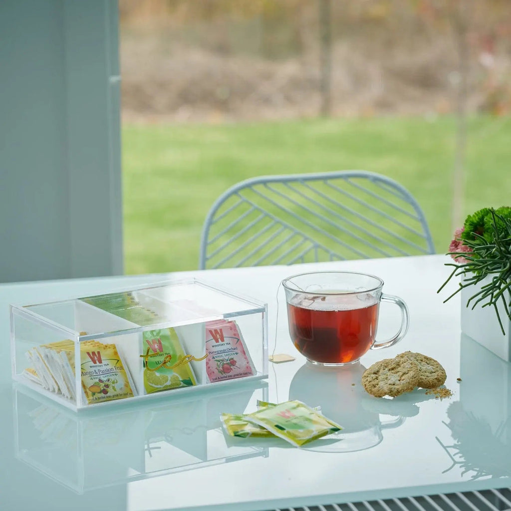 Waterdale Collection silverware tea caddy with clear glass compartments displaying tea bags and accessories on white table near window