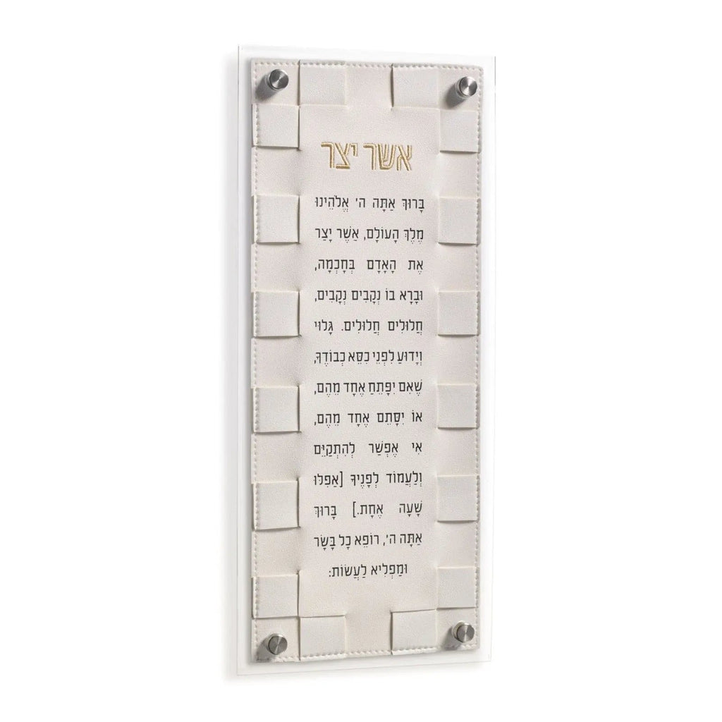 Woven Asher Yatzar wall art in cream with Hebrew text and textured brick-pattern background, mounted with metal corners.