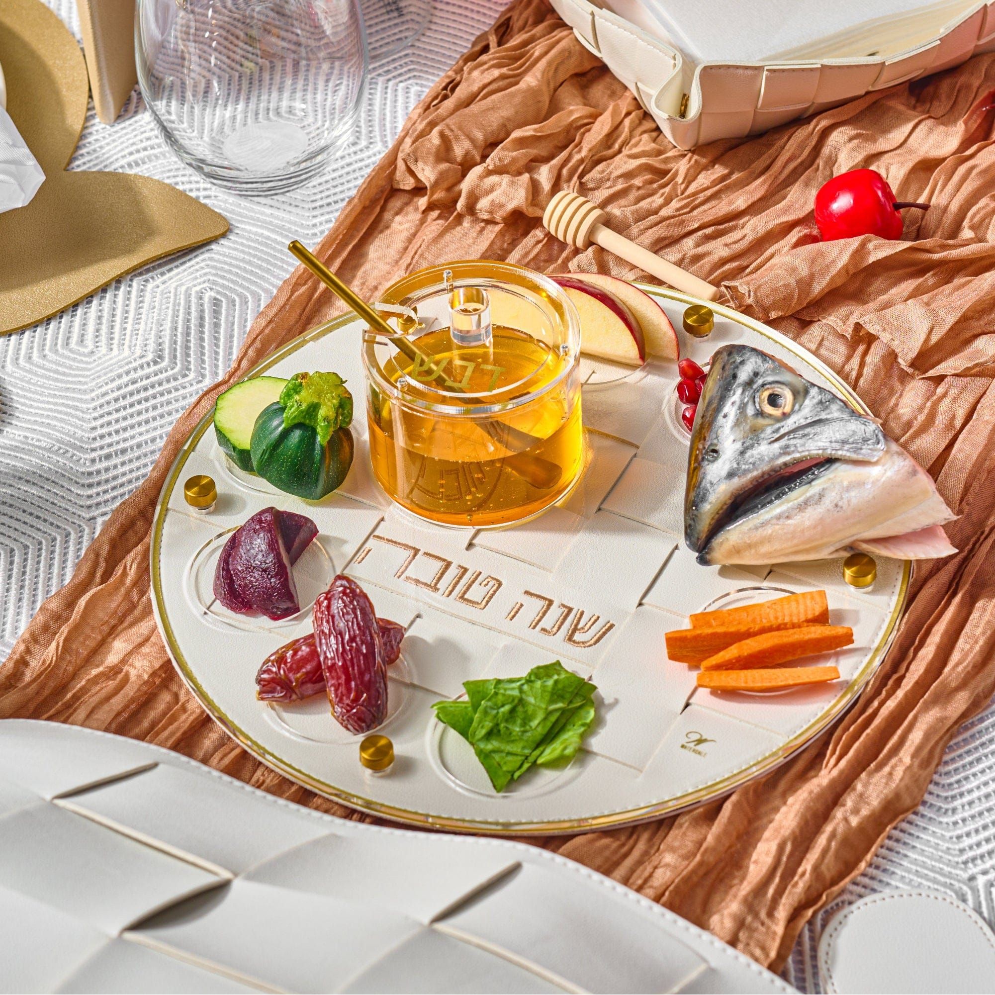 Gold Woven Simanim Tray with fish head, honey dish, and other items on top of it